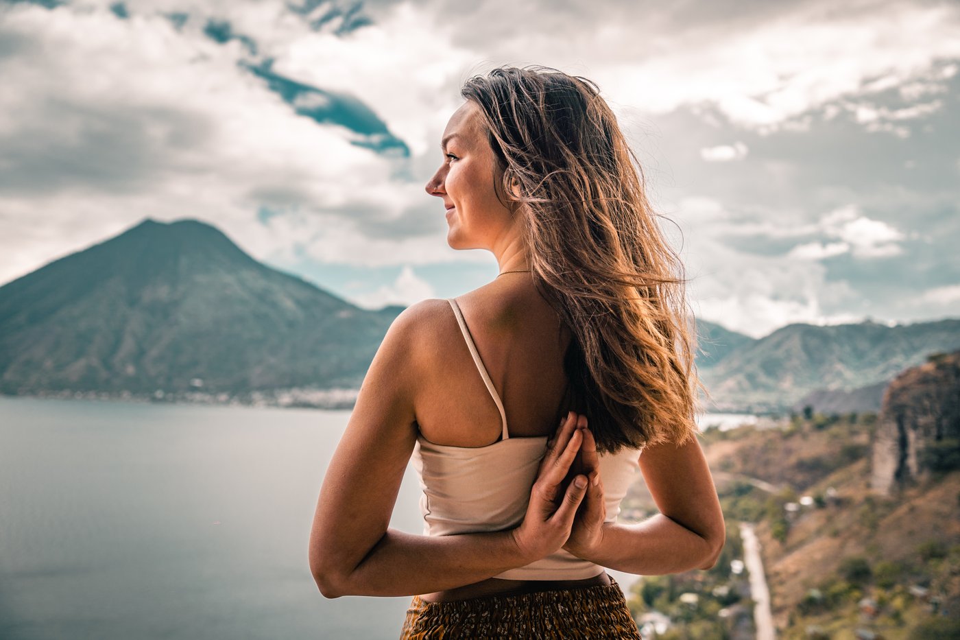 Laura Born with hands in prayer position behind her back, overlooking Lake Atitlán and its volcanoes